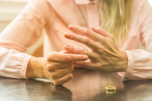 Protecting Assets During Divorce concept | woman's hands, removing wedding ring