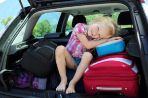 young girl sitting in back of car with luggage | child relocation laws Arizona